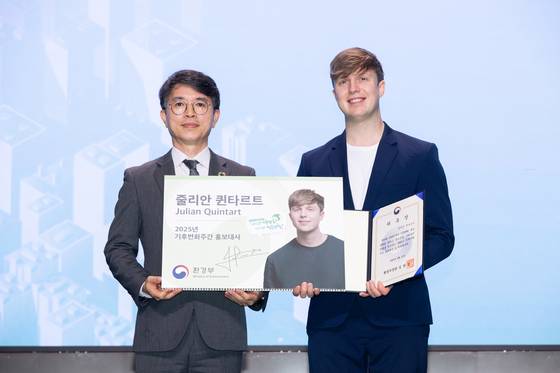 김완섭 환경부 장관이 지난 4월 21일 서울 강서구 코엑스 마곡에서 열린 2025년 기후변화주간 개막식에 참석해 벨기에 출신 방송인 줄리안 퀸타르트에게 기후변화주간 홍보대사 위촉장을 전달하고 기념 촬영을 하고 있다. 뉴스1