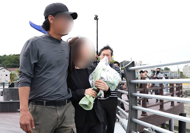 갯벌 고립자를 구하다가 순직한 해양경찰관 이재석 경사의 유족인 어머니와 사촌 형이 22일 오후 인천시 옹진군 영흥도 하늘고래 전망대에서 국화꽃을 들고 고인을 추모하며 오열하고 있다. [연합]