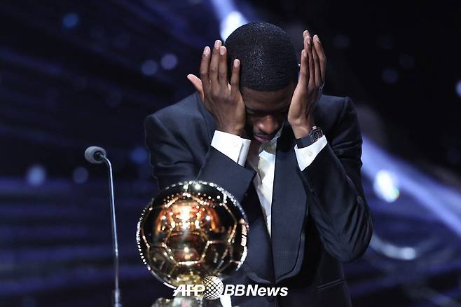 파리 생제르맹(PSG) 공격수 우스만 뎀벨레가 23일(한국시간) 프랑스 파리의 샤틀레 극장에서 열린 2025 발롱도르 시상식에서 발롱도르 1위로 선정돼 시상대에 올라 눈물을 닦고 있다. /AFPBBNews=뉴스1