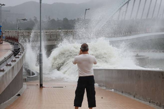 24일 홍콩의 한 시민이 방파제 앞에서 파도치는 모습을 사진으로 남기고 있다. EPA연합뉴스