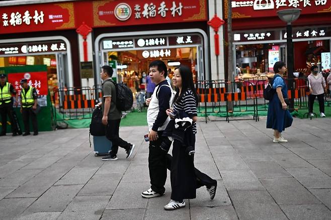 중국 베이징 시내 상권에서 젊은 남녀가 거리를 걷고 있다. 지난달 중국의 산업생산과 소매판매 증가율이 모두 둔화하며 경기 침체 우려가 커지고 있다. 2025.9.15 AFP 연합뉴스