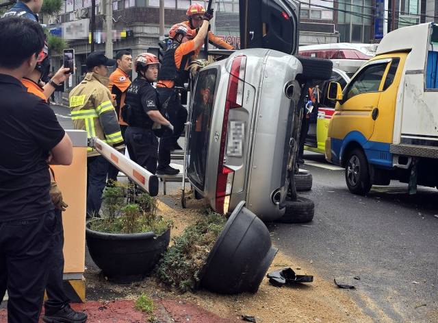 25일 오후 울산 동구 방어동에서 60대 여성이 몰던 그랜저 차량이 식당 건물과 화물차를 잇따라 충돌한 뒤 옆으로 넘어져 있다. 연합뉴스