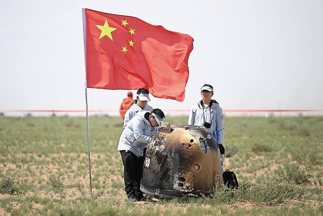 지난해 6월 중국 네이멍구 사막에 착륙한 창어 6호의 캡슐을 중국 국가항천국 관계자 등이 살펴보고 있다. 이날 중국은 무인 탐사선 창어 6호로 달 뒷면의 토양 표본을 세계 최초로 채취하고 캡슐에 실어 지구로 가져오는 데 성공했다./연합뉴스
