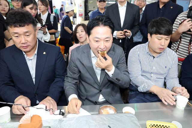 장동혁(가운데) 국민의힘 당대표가 25일 오전 대전시 동구 중동 중앙시장을 찾아 음식을 먹고 있다.<공동취재·연합뉴스>