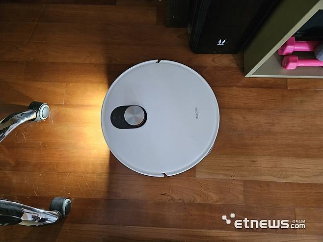 의자와 물건으로 진입이 복잡한 책상 밑을 진입해 청소하고 있다. (사진=배옥진)