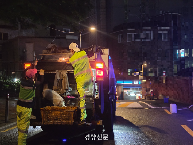 25일 새벽 서울의 한 대학가 인근 골목에서 환경미화원들이 발판에 올라서고 있다. 우혜림 기자