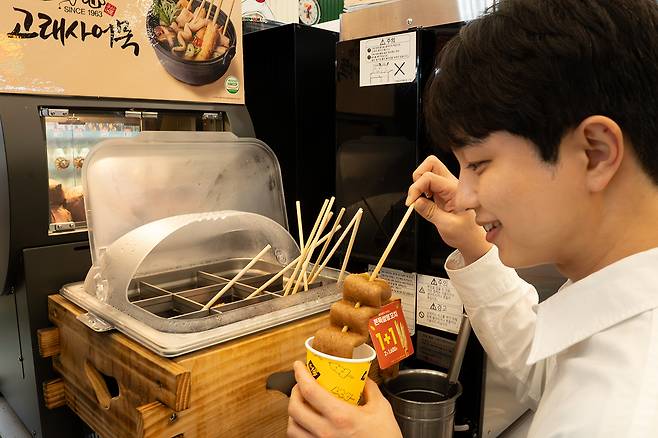 Convenience store chain 7-Eleven began selling popular winter snacks such as roasted sweet potatoes, five types of eomuk (fish cakes) and three kinds of bungeoppang (fish-shaped pastries) starting Sept. 22. A customer selects roasted sweet potatoes at a store. [7-ELEVEN]