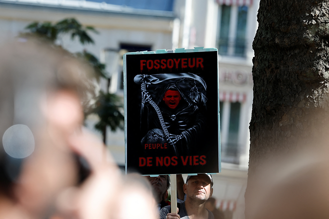 지난 18일(현지시간) 프랑스 파리에서 열린 전국 총파업·시위에서 한 시위자가  에마뉘엘 마크롱 대통령을 풍자한 피켓을 들고 있다. [로이터]