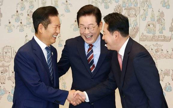 이재명 대통령이 9월 8일 서울 용산 대통령실 청사에서 열린 여야 지도부 오찬 회동에 앞서 정청래(왼쪽) 더불어민주당 대표와 장동혁 국민의힘 대표가 악수하는 모습을 보며 밝게 웃고 있다. 뉴시스