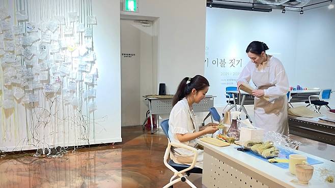 치유공예 그룹 ‘손의 기억’의 신소연 대표와 연구진이 전시장 ‘아기 이불 짓기’ 공간에서 작업을 준비하고 있다.