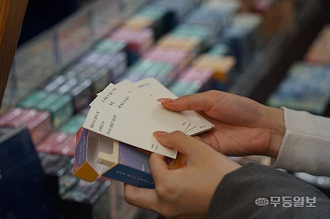 28일 오전 한 시민이 '주머니시' 부스에서 담배갑 모양 상자에서 작은 시를 꺼내 읽고 있다.