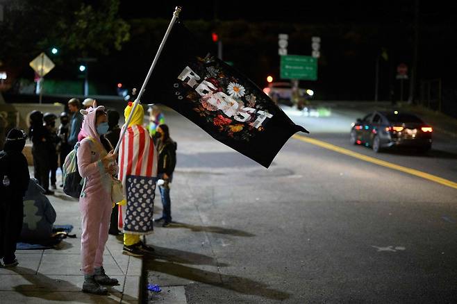지난 27일(현지시간) 미국 오리건주 포틀랜드의 미국 이민세관단속국(ICE) 건물 밖에서 한 시위자가 깃발을 흔들고 있다. AFP연합뉴스