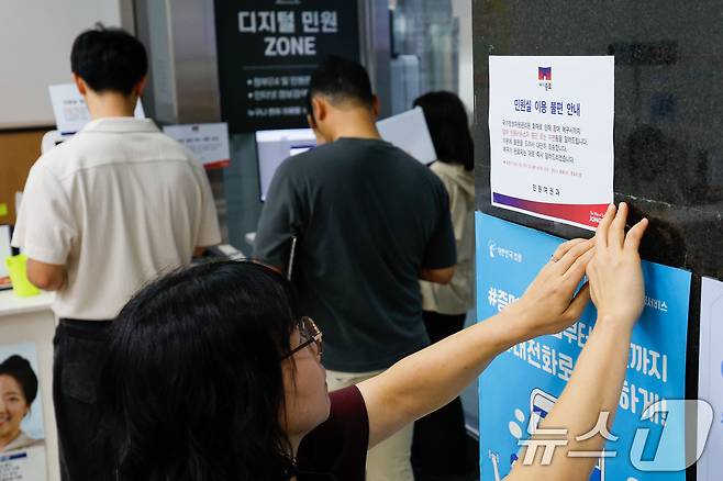 정부가 대전 국가정보자원관리원(국정자원) 전산실에서 발생한 화재로 중단된 행정정보시스템 복구에 총력을 기울이고 있는 29일 오전 서울 종로구청에서 직원이 민원실 이용 불편 안내문을 부착하고 있다. 2025.9.29/뉴스1 ⓒ News1 안은나 기자