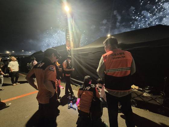 불꽃축제가 한창인 지난 27일 오후 8시쯤, 소방대원들이 어지럼증을 호소하는 남성을 둘러싸고 혈압을 재고 있다. 전율 기자
