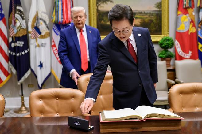 (워싱턴=뉴스1) 류정민 특파원 = 지난 8월 25일(현지시간) 이재명 대통령이 한미정상회담에 앞서 미 백악관 루즈벨트룸에서 방명록에 서명하려고 펜을 잡으려는 순간 도널드 트럼프 미국 대통령이 뒤에서 의자를 당겨 주고 있다. 2025.08.31(백악관 제공. 재판매 및 DB금지)  Copyright (C) 뉴스1. All rights reserved. 무단 전재 및 재배포,  AI학습 이용 금지. /사진=(워싱턴=뉴스1) 류정민 특파원