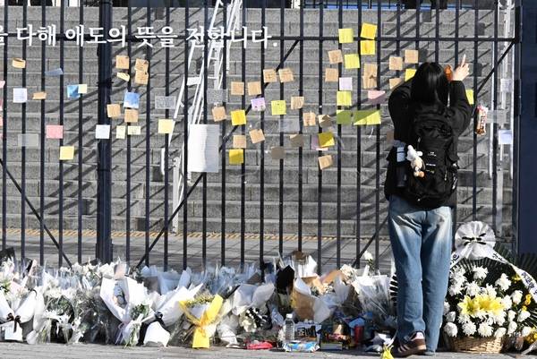 4월 8일 한 청년이 창원NC파크 4번 게이트 출입문에 설치된 추모벽에 조화를 놓은후 추모글을 남기고 있다. 3월 29일 창원NC파크에서 구조물 추락으로 인명사고가 발생 했다./김구연 기자