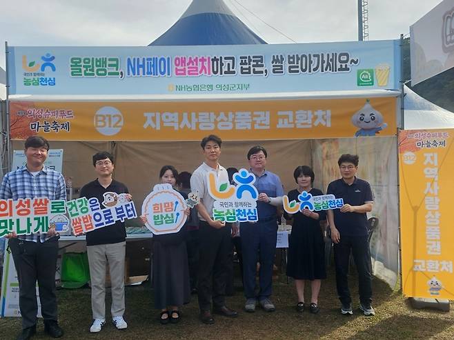 ▲ 9월 26일 제8회 의성슈퍼푸드마늘축제장에서 NH농협 의성군지부(지부장 이진석·사진 왼쪽 네번째) 직원들이 농심천심 운동 홍보부스를 운영하며 기념촬영을 하고 있다. NH농협 의성군지부
