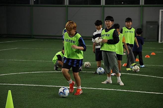 축구교실에서 드리블을 연습하는 아이들