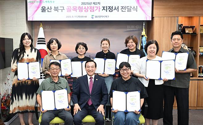 울산 북구가 조례 개정을 통해 ‘골목형 상점가’ 지정기준을 완화함으로써 10개 상인회가 신규로 지정돼 지난 11일 구청장실에서 골목형 상점가 지정서 전달식을 가지고 박천동 북구청장(앞줄 가운데)과 기념촬영을 했다. [울산 북구청 제공]