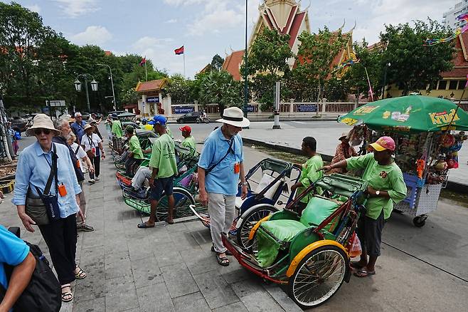 캄보디아 프놈펜에서 관광객들이 지난 25일(현지시간) 인력거를 타고 관광에 나서고 있다. [AP]
