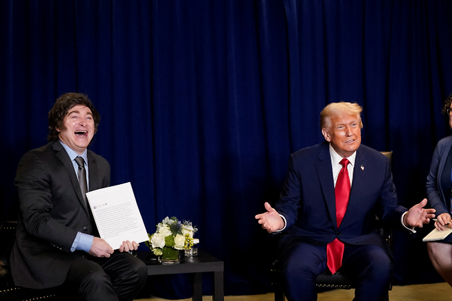 지난 23일 유엔총회 도중 도널드 트럼프 미국 대통령을 만난 하비에르 밀레이(왼쪽) 밀레이 대통령이 자신을 칭찬하는 내용의 문서를 전달받자 함박웃음을 짓고 있다. 뉴욕 로이터 연합뉴스