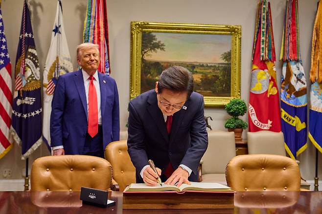 이재명 대통령이 지난 8월 25일(현지시간) 미국 워싱턴 DC 백악관에서 도널드 트럼프 미국 대통령이 지켜보는 가운데 방명록을 작성하고 있다./대통령실