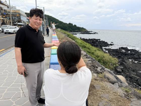 좌윤철 제주시 도두동장(왼쪽)이 지난달 29일 제주시 도두동 무지개해안도로를 찾아 관광객의 질문에 답변하고 있다. 최충일 기자