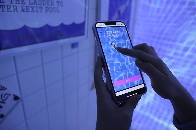 A participant in an escape room game at Real World Seongsu solves a mission using a smartphone. [REAL WORLD SEONGSU]