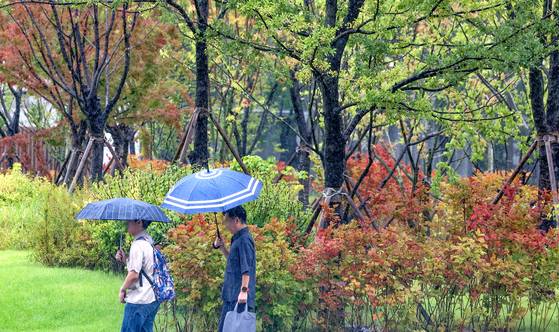 People walk with umbrellas near Gwanghwamun Square in central Seoul on Sept. 24. [NEWS1]