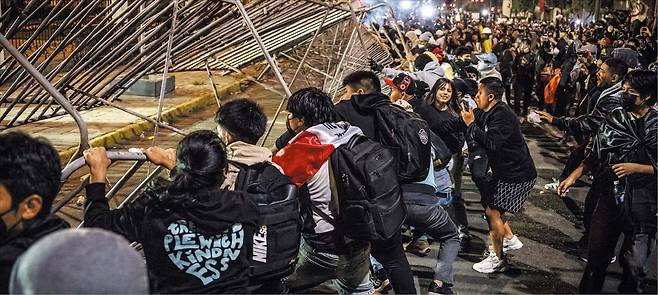 경제 불평등과 기득권 부패에 분노하는 ‘Z세대 시위’가 전 세계로 확산하고 있다. 지난달 21일 필리핀 수도 마닐라 시위 현장에서 한 청년이 경찰 저지선을 뚫겠다며 카트를 밀고 있다(위). 같은 달 28일 페루 수도 리마에선 분노한 청년들이 바리케이드를 철거하고 있다(아래). /AP EPA 연합뉴스