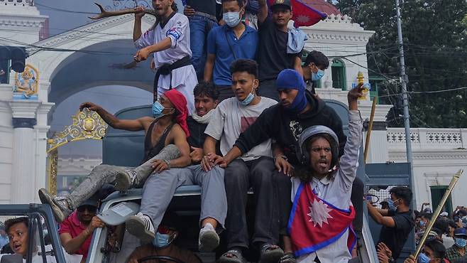 지난달 9일 네팔 수도 카트만두에서 반정부 시위대가 정부 부처가 모여 있는 청사를 불태운 뒤 환호하고 있다. 시위는 네팔 정부의 소셜미디어 차단 조치로 촉발됐다. 카트만두=AP 뉴시스