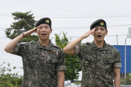 BTS members RM, left, and V salute after being discharged from mandatory military service in Chuncheon, Gangwon on June 10. [AP/YONHAP]