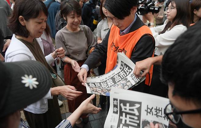 4일 일본 도쿄에서 다카이치 사나에 총재의 당선 소식이 실린 신문 호외를 받기 위해 몰려든 시민들. [AP 연합뉴스]