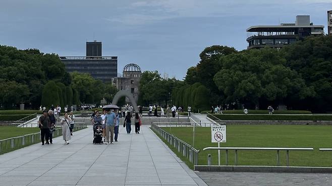 지난 24일 방문한 히로시마 평화기념공원 내부 평화의 불 앞으로 관광객들이 지나가고 있다. 일직선 상 너머에는 히로시마 원폭을 상징하는 원폭 돔이 위치해 있다. <사진=정수민 기자>