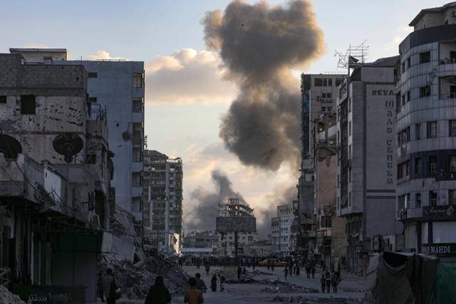 팔레스타인 주민들이 6일 가자지구 가자시티 알사라야 광장에서 이스라엘의 군사 작전으로 연기가 피어오르자 이동하고 있다. 가자시티=EPA 연합뉴스