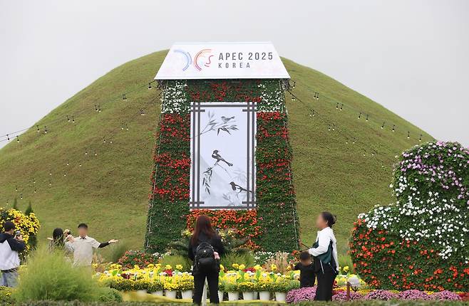 황남동 고분군에 APEC 홍보 꽃 조형물  (경주=연합뉴스) 박세진 기자 = 추석 연휴 닷새째인 7일 경북 경주 황남동 고분군에 설치된 APEC 홍보 꽃 조형물을 배경으로 관광객들이 기념 촬영을 하고 있다. 2025.10.7 psjpsj@yna.co.kr