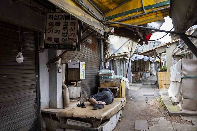 한 상인이 가게 앞 평상에 누워 낮잠을 자고 있다.