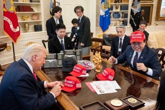 지난 4월 16일(현지시간) 관세 협상을 하기 위해 미국 백악관을 찾은 일본 측 협상 대표 아카자와 료세이(오른쪽) 경제재생상이 도널드 트럼프(왼쪽) 미 대통령이 사인한 마가(MAGA·미국을 다시 위대하게) 모자를 쓰고 웃고 있다. 백악관 제공