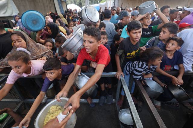 지난달 30일(현지 시간) 가자지구 중부 누세이라트 급식소에서 팔레스타인의 아이들이 자선 단체가 무료로 나눠주는 음식을 전달받고 있다. AFP연합뉴스