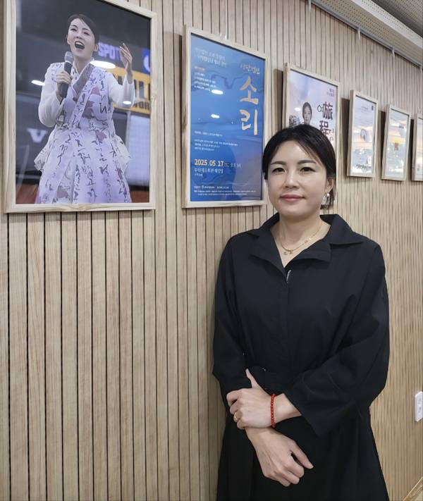 각종 공연 포스터와 상장을 배경으로 서 있는 정자경 대표.