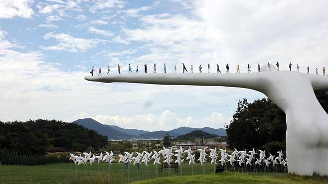 산이정원 하늘마루에 설치된 유영호 작가의 '브리지 오브 휴먼'. 몸을 숙여 스스로 다리 역할을 하는 거인의 두 팔 위에 42명의 인간 군상이 보인다. 사진=박범준 기자