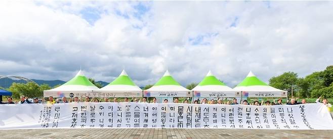 ▲ 제579돌 한글날을 맞아 9일 성주 성밖숲에서 열린 '한글의 혼, 붓 끝에 담다' 행사에서 서예인과 시민들이 대형 천 위에 '훈민정음 서문'을 붓으로 쓰고 관계자들이 기념촬영을 하고 있다. 성주군