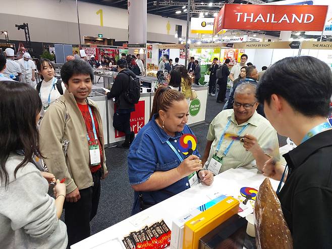 호주 시드니 국제컨벤션센터에서 열린 FFA의 한국 부스에서 나눠주는 태극 부채를 참관객이 받고 있다. /윤희훈 기자