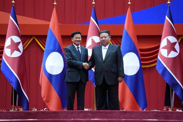 통룬 시술릿(왼쪽) 라오스 국가주석이 7일 북한 평양에서 김정은 북한 국무위원장과 악수하고 있다. 라오티안타임스 캡처