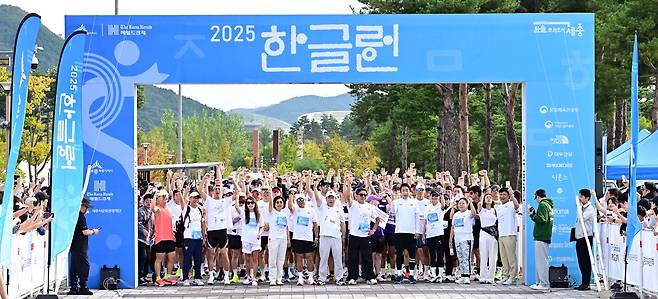 Singer Kim Chang-yeol (third from left),  marathoner Lee Bong-ju (sixth from left), Sejong Mayor Choi Min-ho (seventh from left) , Herald Media Group CEO Choi Jin-young (seventh from right), and singer Sean (fifth from right) join participants for a group photo at the starting line of the 2025 Hangeul Run in Sejong Lake Park on Thursday, celebrating the 579th Hangeul Day. (Lee Sang-sub/The Korea Herald)