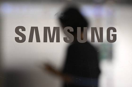 A woman walks past a logo of Samsung Electronics displayed on a glass door at the company's Seocho building in southern Seoul on July 8, 2025. [AFP/YONHAP]