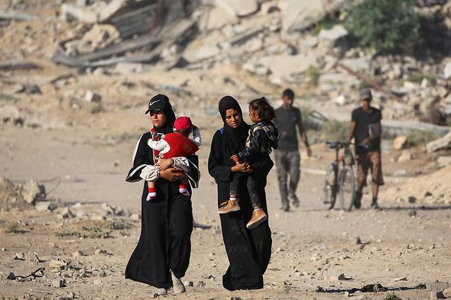 아이를 안은 팔레스타인 여성들이 11일 가자시티로 연결된 가자지구 중부의 길을 따라 걷고 있다. AFP연합뉴스