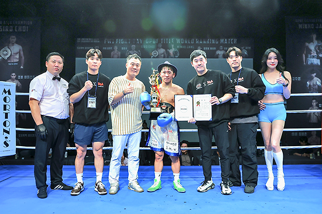 도전자 김우현이 2025년 10월 서울특별시 섬유센터 이벤트홀에서 사단법인 한국복싱커미션 KBM 밴텀급 챔피언 등극 후 기념 촬영을 하고 있다. 세계복싱협회 슈퍼플라이급 아시아 챔피언을 지낸 김우현 왼쪽은 세계복싱평의회 페더급 월드 챔피언에 빛나는 지인진. 사진=FINAL FLASH 제공