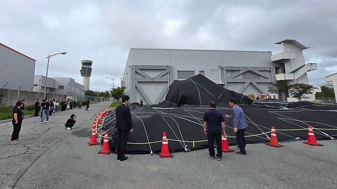 전남 무안국제공항에서 12·29 제주항공 참사 유가족들이 격납고 인근에 보관 중인 사고 여객기 꼬리날개를 살피고 있다. /유가족협의회 제공.