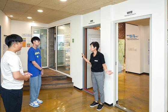 김효선(맨 오른쪽) 해설사가 단열재가 이중으로 들어 있어 일반 문보다 훨씬 무겁고, 이중 개스킷(고무패깅)으로 틈새 바람을 막는 에너지 제로 하우스 단열문에 대해 설명했다.
